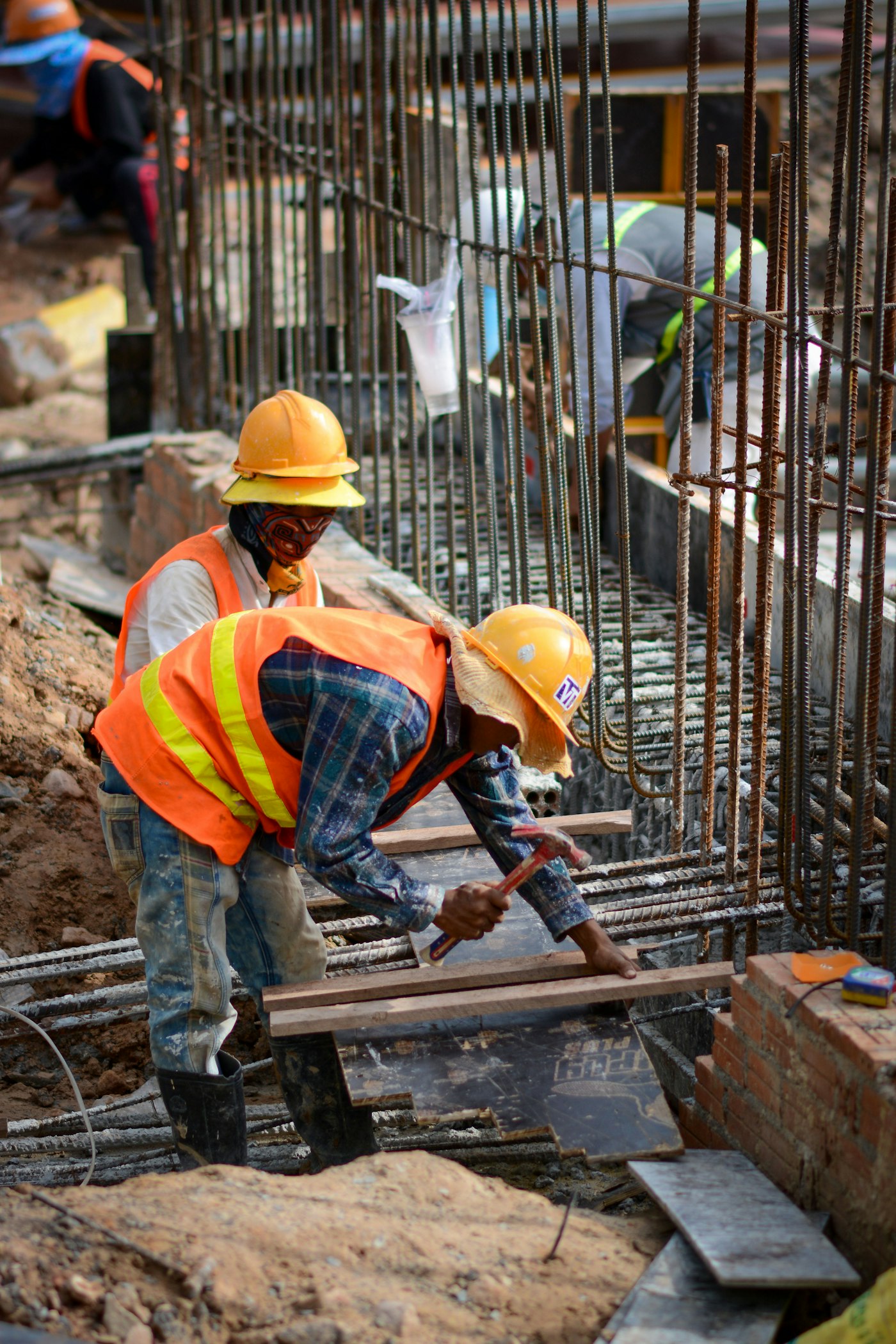 Armadores de capacete e colete montando a armadura de um bloco de fundação