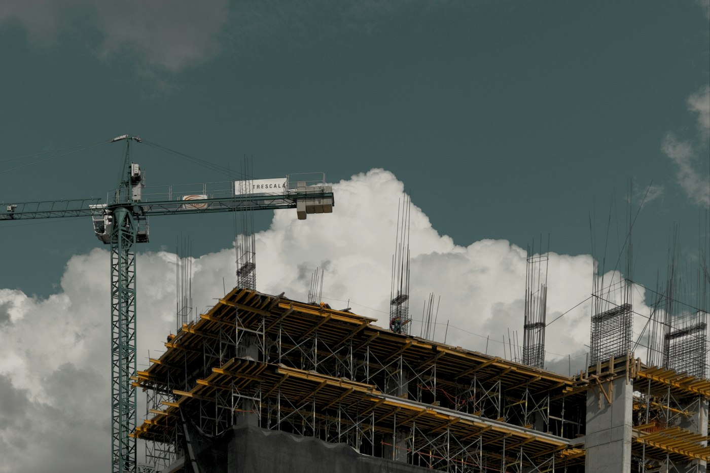 Plano geral da estrutura de concreto com grua, em dia de nuvens