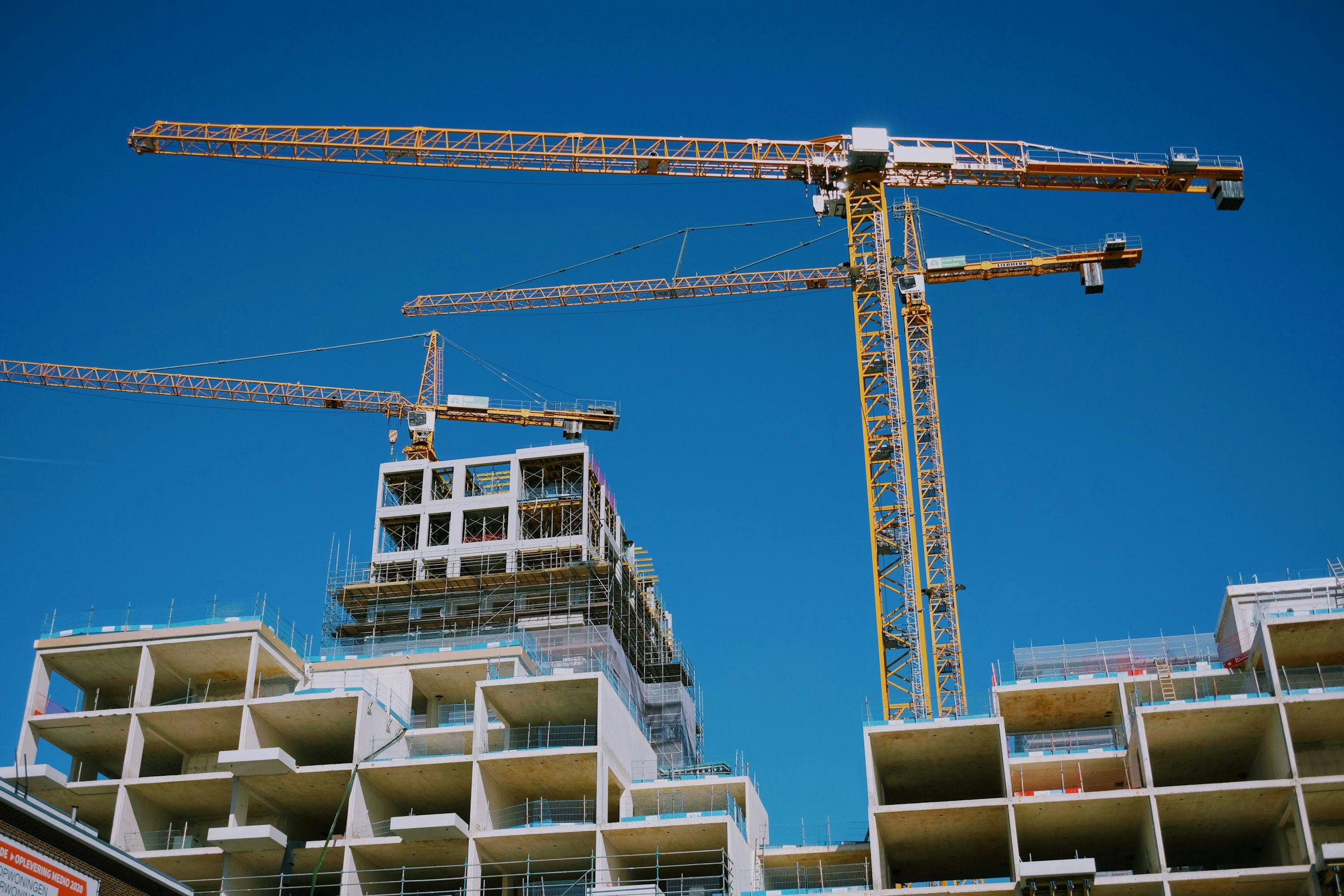 Edifício residencial de concreto em construção com gruas de torre