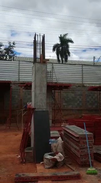 Pilar com forma metálica e painéis empilhados no canteiro